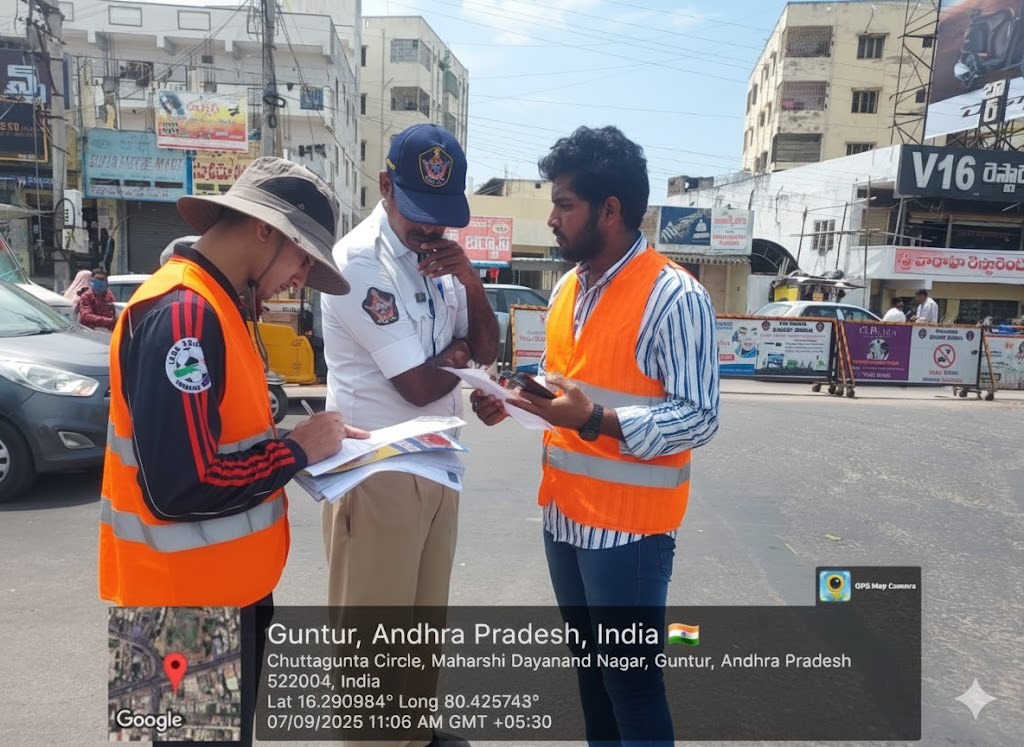 Rakshak volunteers in hi-vis vests running a stakeholder survey with a traffic police officer at Chuttagunta Circle, Guntur